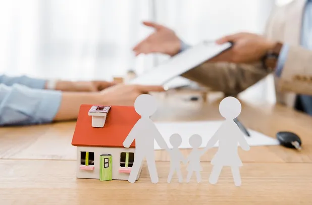Paper cutouts of a family and a house on a table as estate planning documents are reviewed